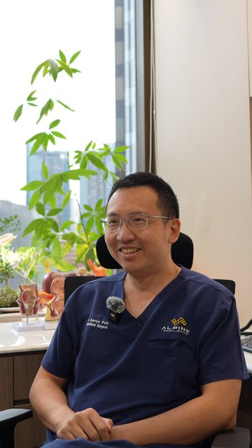 Video frame: a surgeon smiling in his consulting room