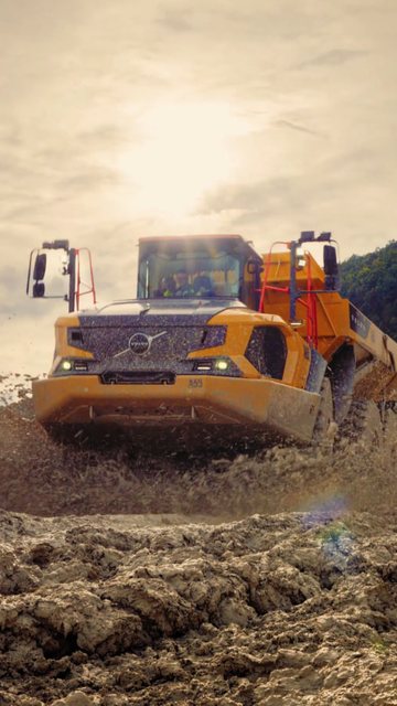 Video frame: an articulated hauler driving through mud